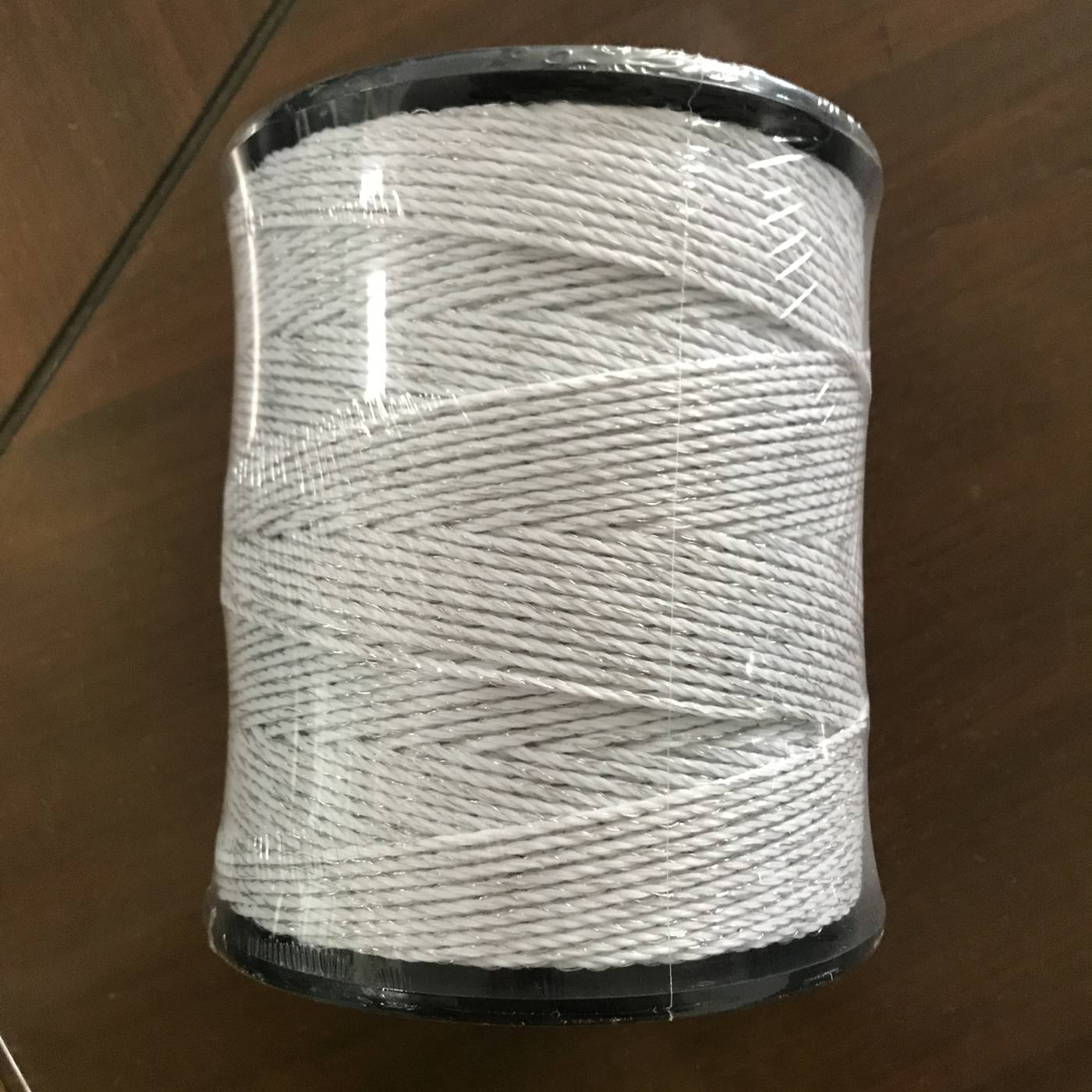 White solid-braided polyester rope on a black spool — classic marine dock line