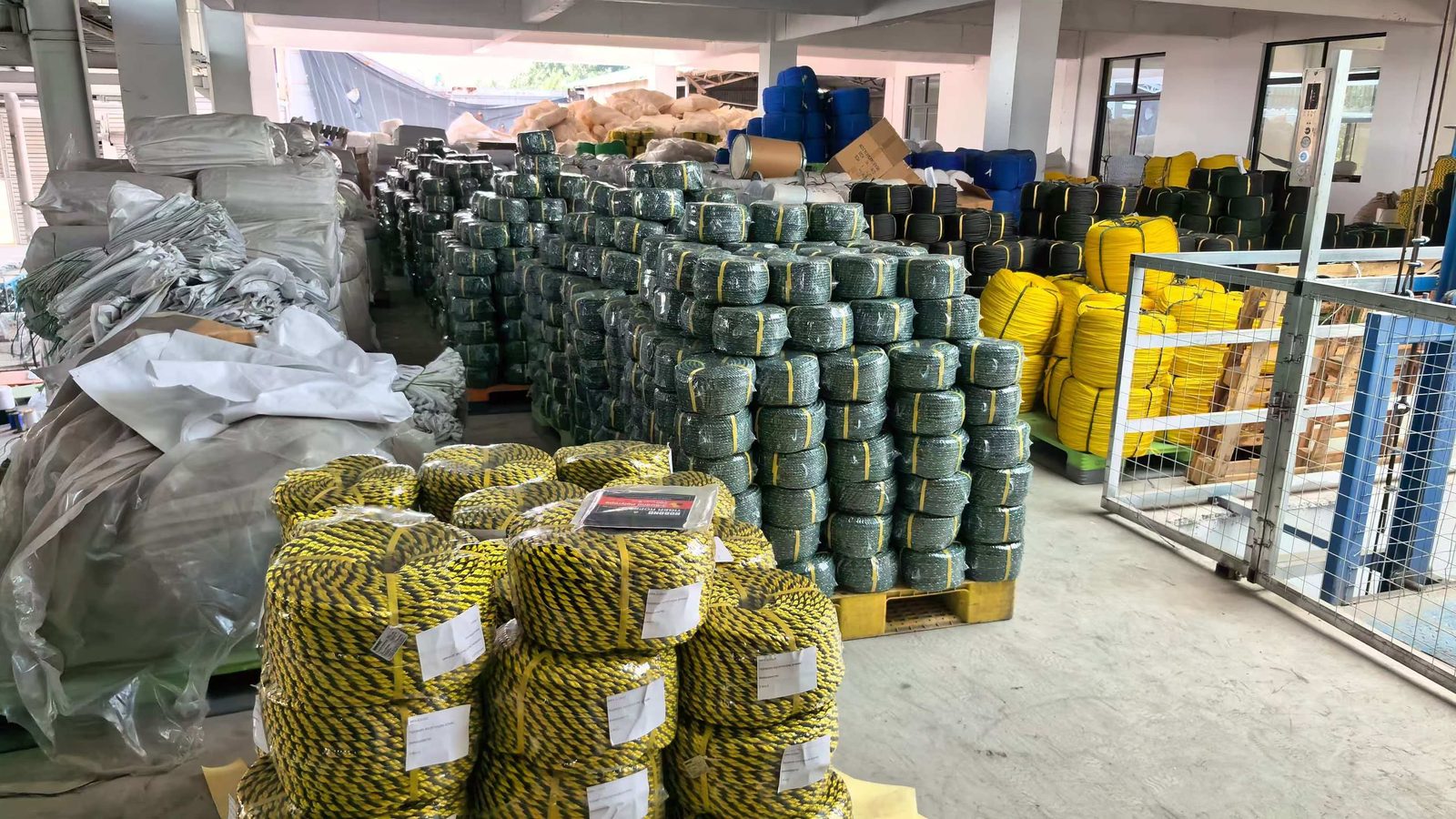 Yellow and black two-tone 3-strand rope coils with white retail labels in a warehouse