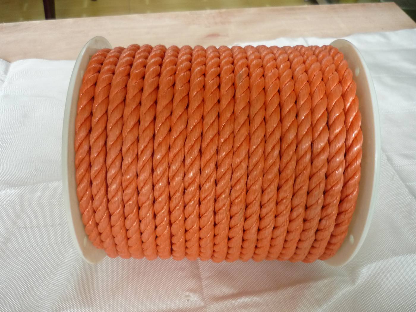 Orange 3-strand twisted polypropylene rope on a small plastic spool — common packing-line rope